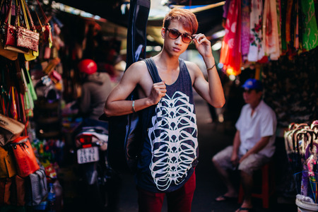 asian artist man with guitar in style sunglasses with guitar at local market in Nha Trang, Vietnamの写真素材