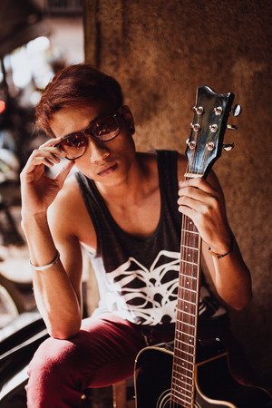 portrait of asian artist man with guitar in style sunglasses with guitarの写真素材