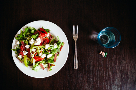 green salad with pills and glass of water top view.の写真素材