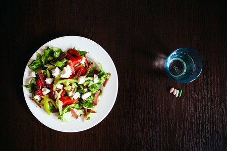 green salad with pills and glass of water top view.の写真素材