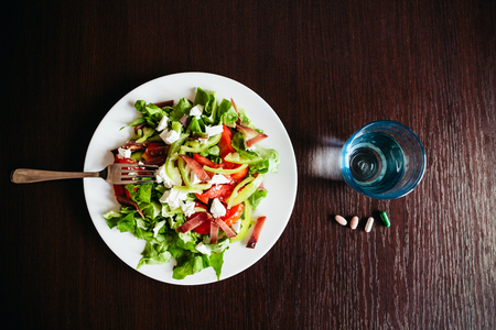 green salad with pills and glass of water top view.の写真素材