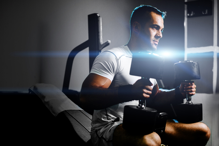bodybuilder guy pumping hands with dumbbellsの写真素材
