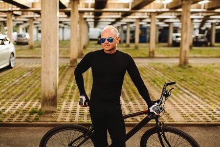 bicycle style man in black sportswear and sunglasses on urban parkingの写真素材