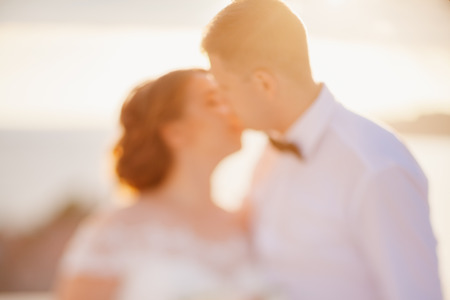destination wedding couple kiss at sunset defocus.の写真素材