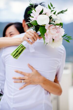 newlyweds holding wedding bouquet togetherの写真素材