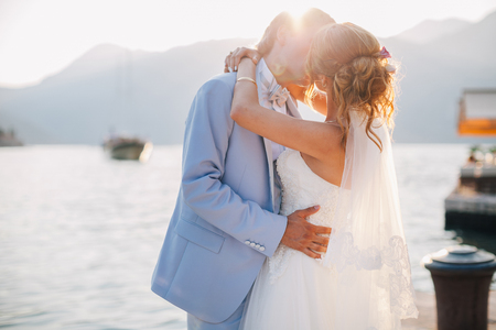wedding couple kiss at sunset with sunlight. Mountains and sea background in Montenegroの写真素材