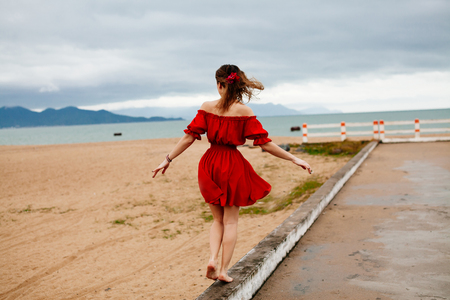 woman balancing on the way. Female with wind in hair on the beach balancing.の写真素材