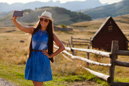 country woman making selfie photo in mountains. Long hair woman travel.の写真素材