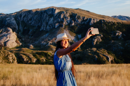 country woman making selfie photo in mountains. Long hair woman travel.の写真素材