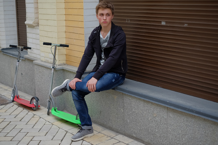 portrait of a boy on scooter in urban street. Fashion boy travel. unfiltered.の写真素材