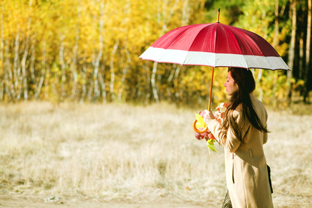 woman walk in autumn forest with umbrellaの写真素材