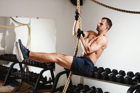 rope climbing workout athlete man in gymの写真素材