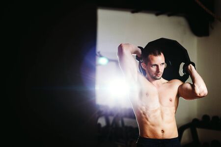 handsome athlete with Weight plate workout in gym. Caucasian male.の写真素材