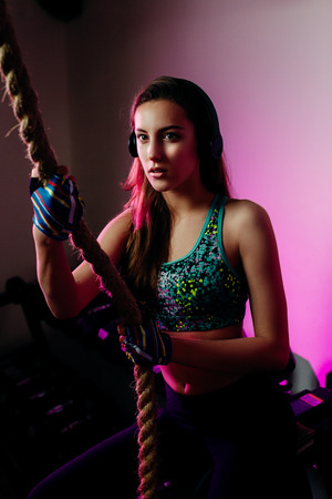 fitness teenage woman in gym. Portrait of woman rope climbing. Fancy girl listen to music.の写真素材