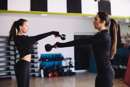 fitness women kettlebell workout in gym. Two women cross fitness workout.の写真素材