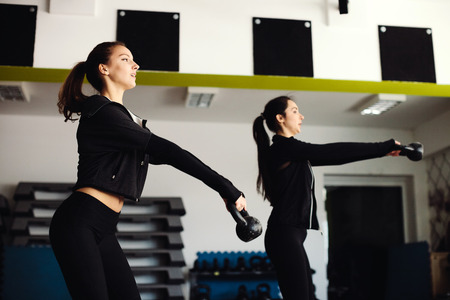 women kettlebell workout in gym. Two girls doing kettlebell exercises.の写真素材