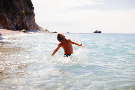 A Boy Swimming In The Sea. Wild beach background.の写真素材