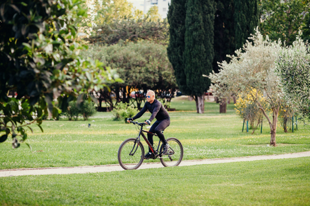 Man Cycling in Park. Caucasian adult man cycling through summer green park.の写真素材