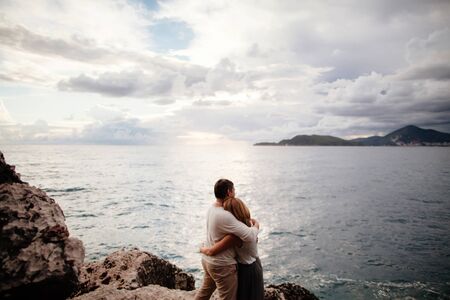 Couple hug on seaside. Cloudy sky and picturesque scenery background.