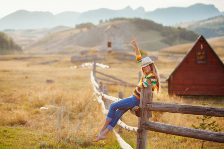 happy woman posing in cowboy hat at countrysideの写真素材
