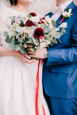 bride and groom holding wedding bouquet. Fine art wedding bouquet. Tanging creamy bouquet wuth roses and peonies.の写真素材