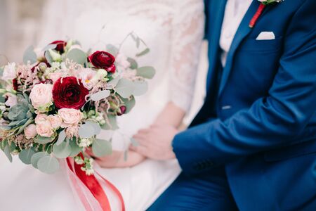 bride and groom holding wedding bouquet. Fine art wedding bouquet. Tanging creamy bouquet wuth roses...