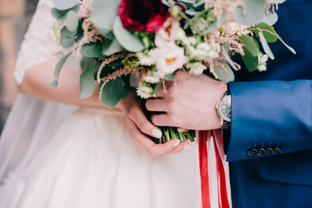 bride and groom holding wedding bouquet. Fine art wedding bouquet. Tanging creamy bouquet wuth roses and peonies.の写真素材