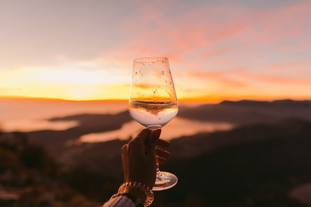 glass of wine at sunset. Woman holding glass of white wine.の写真素材