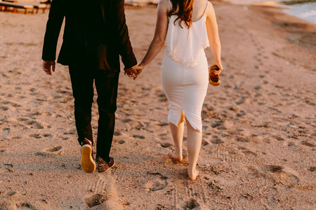 couple walk on sand beach barefoot at sunset. Honeymoonの写真素材