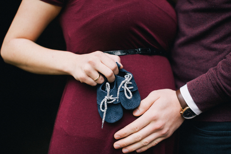Pregnant woman holding baby booties. Belly with booties close upの写真素材
