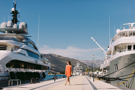 woman walking in sea port with yachts background. travelling on sea yachtの写真素材