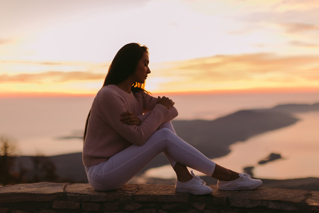 woman dreaming at sunset with mountains view. Aloneの写真素材