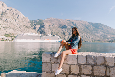 woman sitting on beach with cruise ship view in Montenegro. Kotor bay.の写真素材