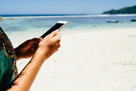 woman using smartphone on beach in tropics. Female travel and use smartphone on beach of Seychelles.の写真素材
