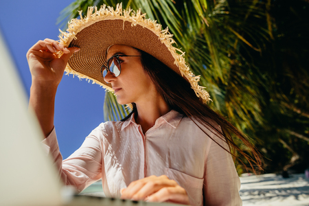 Portrait of freelance Woman in tropics. Working remotely on the laptop computer through the internet. Working while travelling. Summer vacation in Seychelles.の写真素材