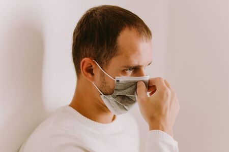 man using face mask for virus prevention during quarantine at home. Virus prevention measures on...