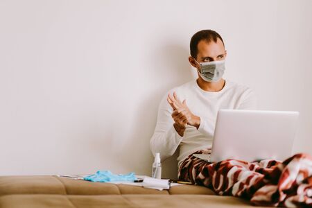 man desinfecting hands with hand sanitizer and working at home. Caucasian male working at home and using alcohol gel to clean hands and skin against virus, germs, bacteria for health care. Stay at homeの写真素材