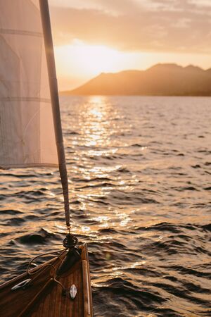 yacht sailing at sunset in sea with mountains view. Romantic sailing yacht at sunset. Poetic and picturesque landscape.の写真素材