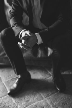man sitting with hands on the knees and fingers locked. Business man nervous and waiting for decision. Black and white.の写真素材