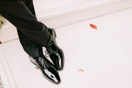 groom wearing black patent shoes outdoors closeup. Businessman standing in stylish shoes outdoors. Artist man.の写真素材