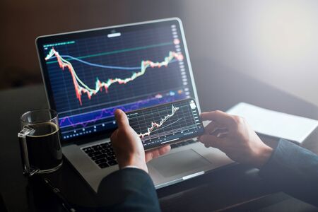 investment stockbroker stock market analysis. Financial investment app graph on phone and laptop....