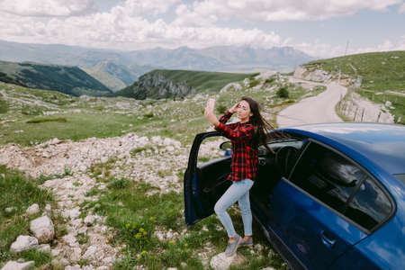 attractive woman travel by car and using smartphone in mountainsの写真素材
