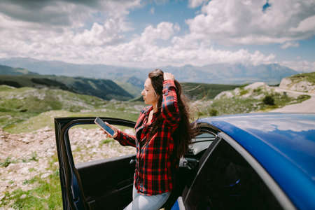 beautiful woman tourist travel by car and browsing smartphone in mountainsの写真素材