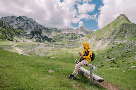 man travel with dog using smartphone at countryside with mountains scenic viewの写真素材