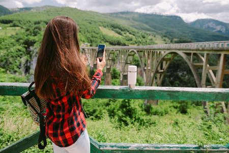 pretty woman traveller using smartphone on vacations in mountains