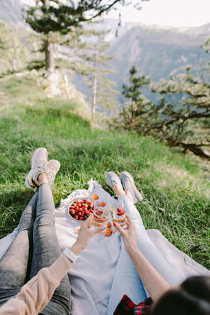 women drink summer cocktails outdoors with mountains view