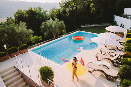 beautiful woman relax on inflatable pool toy unicorn in swimming poolの写真素材