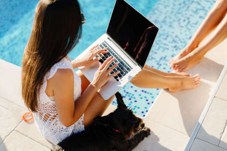 women using laptop work outdoors with cute dogの写真素材