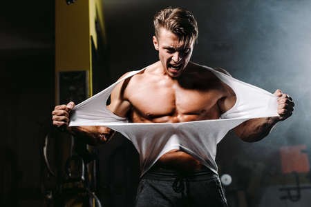 Sexy muscular man ripping shirt in gym emotionally and furiousの写真素材