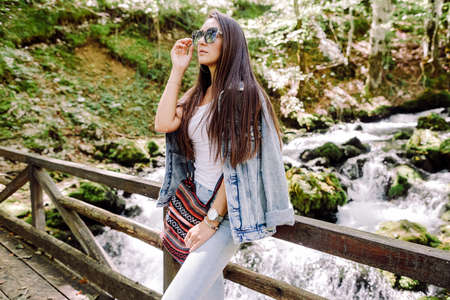 woman relax in autumn forest with waterfall backgroundの写真素材